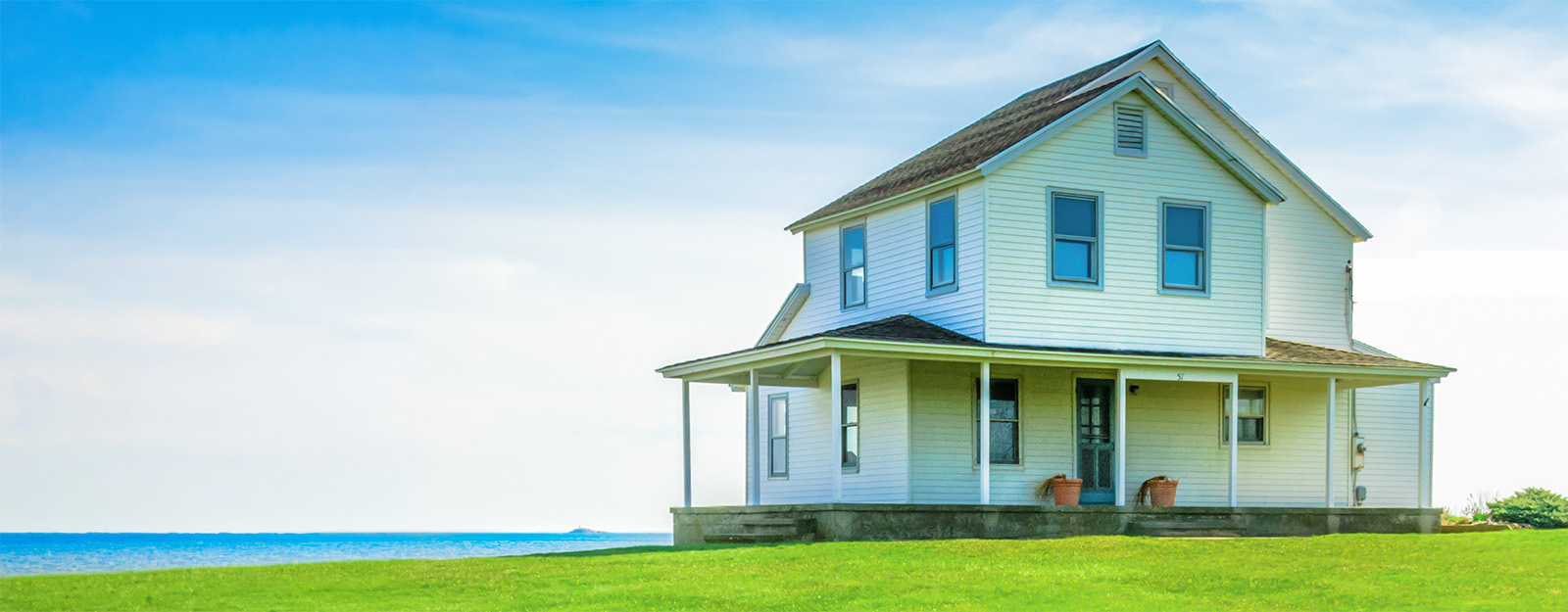 White farmhouse with pristine green lawn on a sunny day, illustrating residential lawn protection and curb appeal