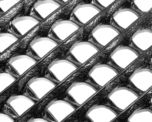 Close-up of Tenax Trackway HDPE ground protection mat showing the large rounded square grid cell pattern and heavy-duty black construction