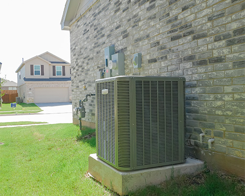 Standby generator unit installed in a residential garden beside a stone wall, representing utility and service equipment access that requires ground protection
