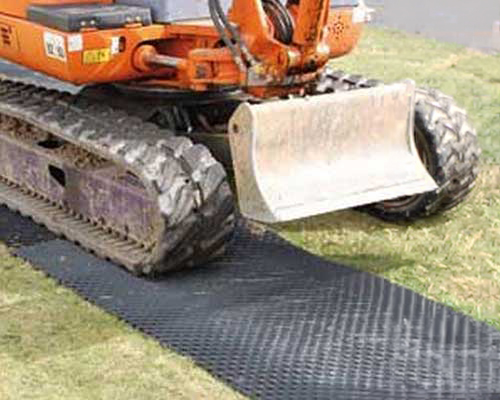 Mini excavator operating on Tenax Trackway HDPE ground protection mats at an active construction site