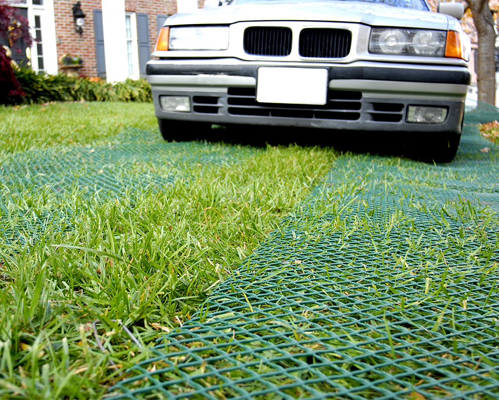 Car parked on a sunny reinforced green grass surface, showing Tenax ground protection mesh installed result