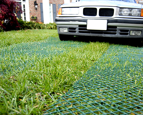 Car parked on a sunny reinforced green grass surface, showing Tenax ground protection mesh installed result