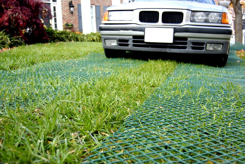 Car parked on a sunny reinforced green grass surface, showing Tenax ground protection mesh installed result