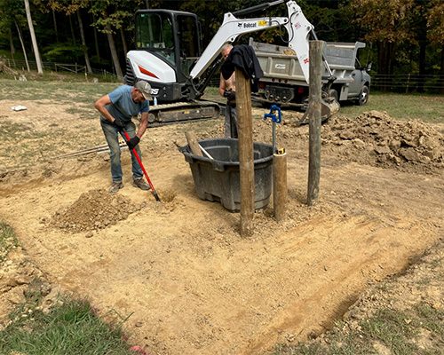 Construction worker operating machinery on Tenax ground protection mesh at an active construction site