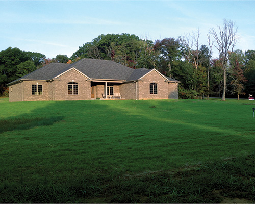 Residential house with a wide reinforced green lawn, showing Tenax mesh providing a clean turf result