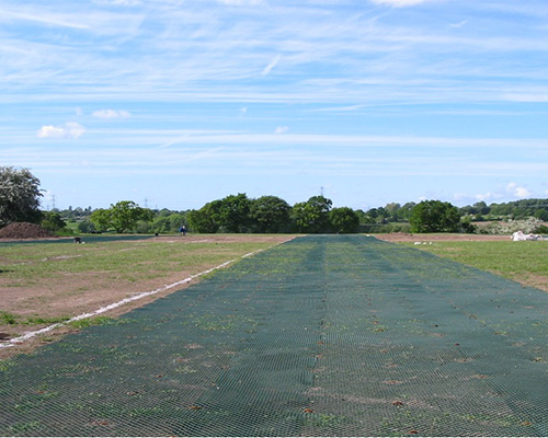 Tenax GP Flex ground protection mesh rolled out across a field during installation, showing green mesh being laid at scale