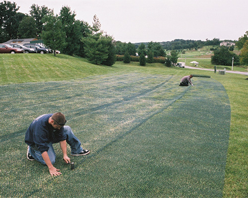 Installer working on Tenax ground protection mesh across a fairway at Hayfield Golf Club, showing golf course reinforcement